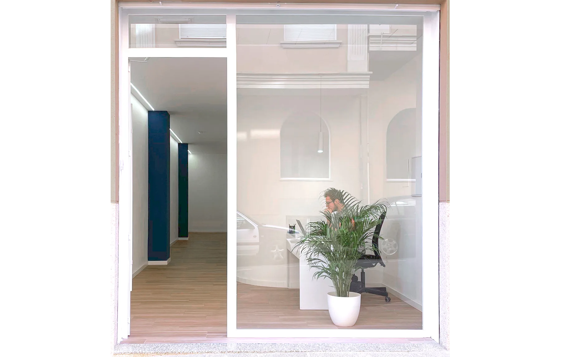 Fachada de cristal de la clínica EPP con vista al interior de la recepción, mostrando una oficina luminosa y una planta decorativa.