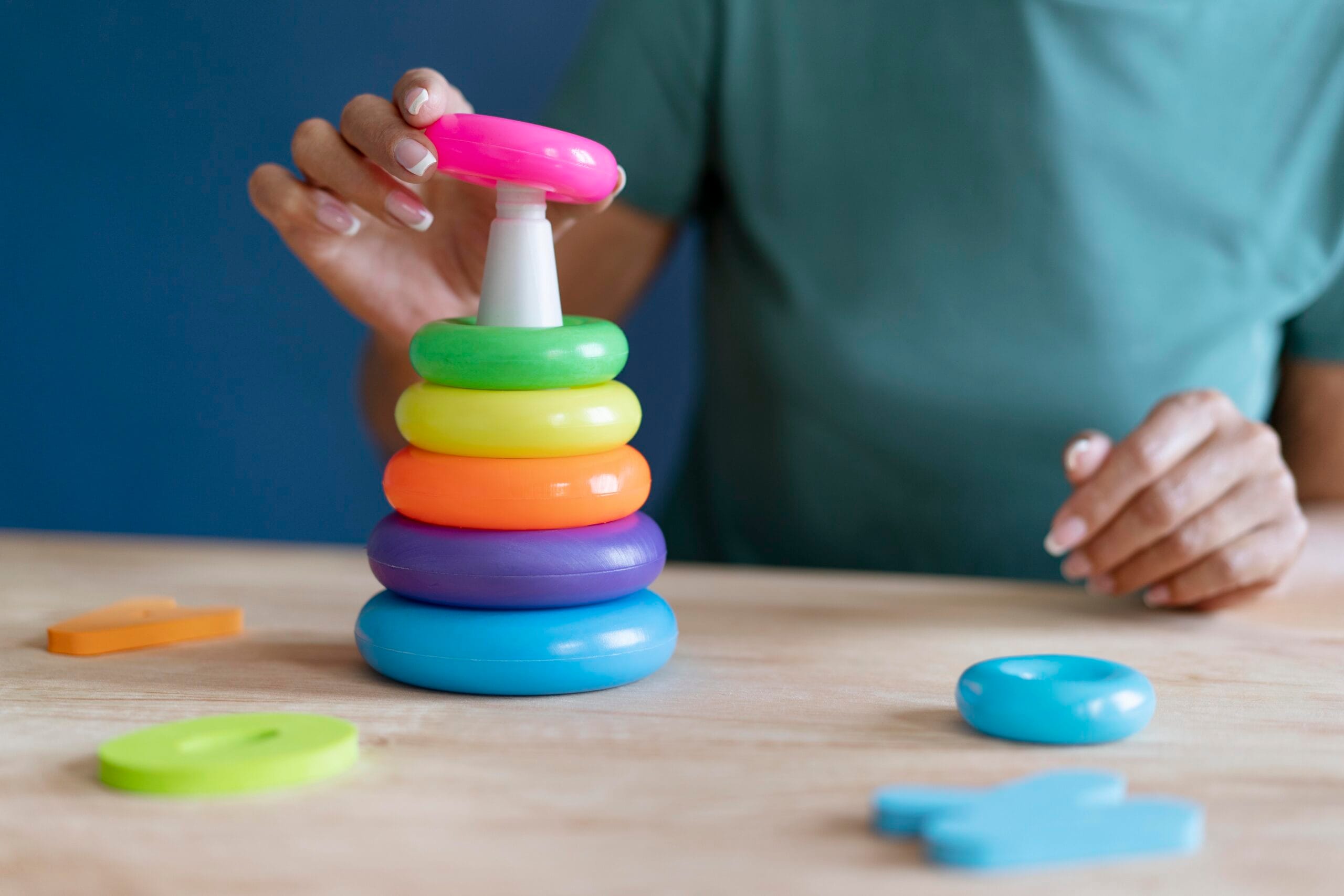 Una profesional de Clínica EPP utiliza un juguete de anillas apilables de colores para trabajar la coordinación ojo-mano y el desarrollo cognitivo en una sesión de terapia.